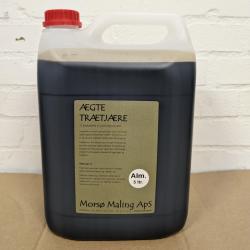 På billedet ser du en 5-liters dunk trætjære. Spanden har en neutral farve med klare nuancer. Forgrunden og baggrunden er en ensfarvet lysere grå, hvilket giver et minimalistisk og professionelt udtryk. Teksten på dåsen er skrevet i sort, hvilket skaber en klar kontrast for let aflæsning. Den primære tekst angiver, at indholdet er 